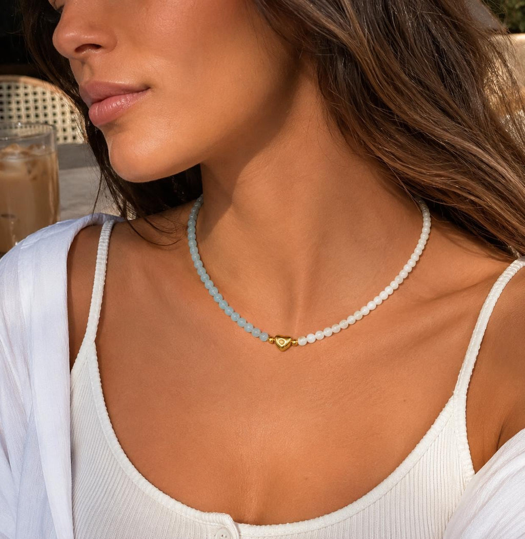 Collier aigue-marine et nacre blanche à cœur doré porté au cou