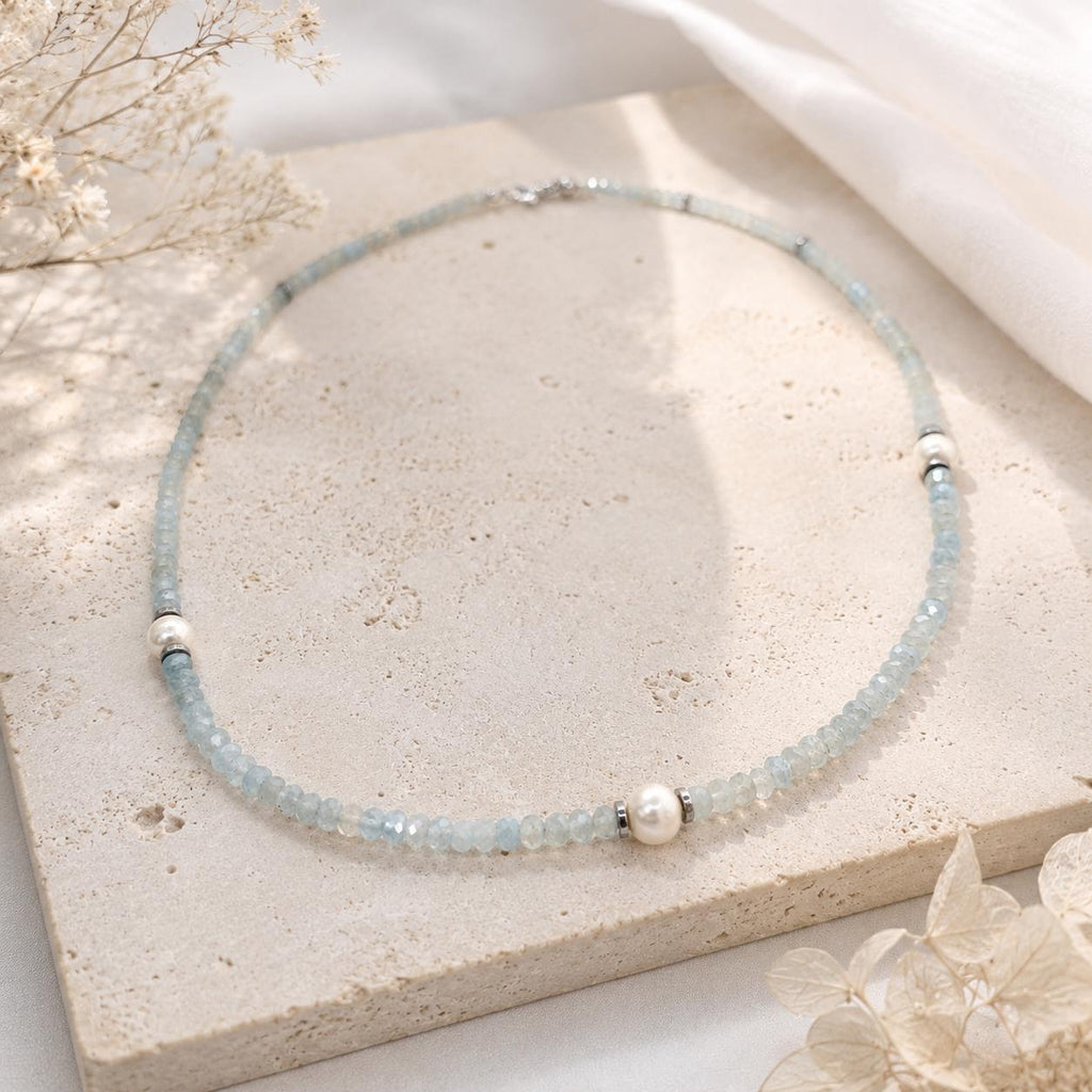 Collier aigue-marine et perle d’eau douce posé sur une pierre claire