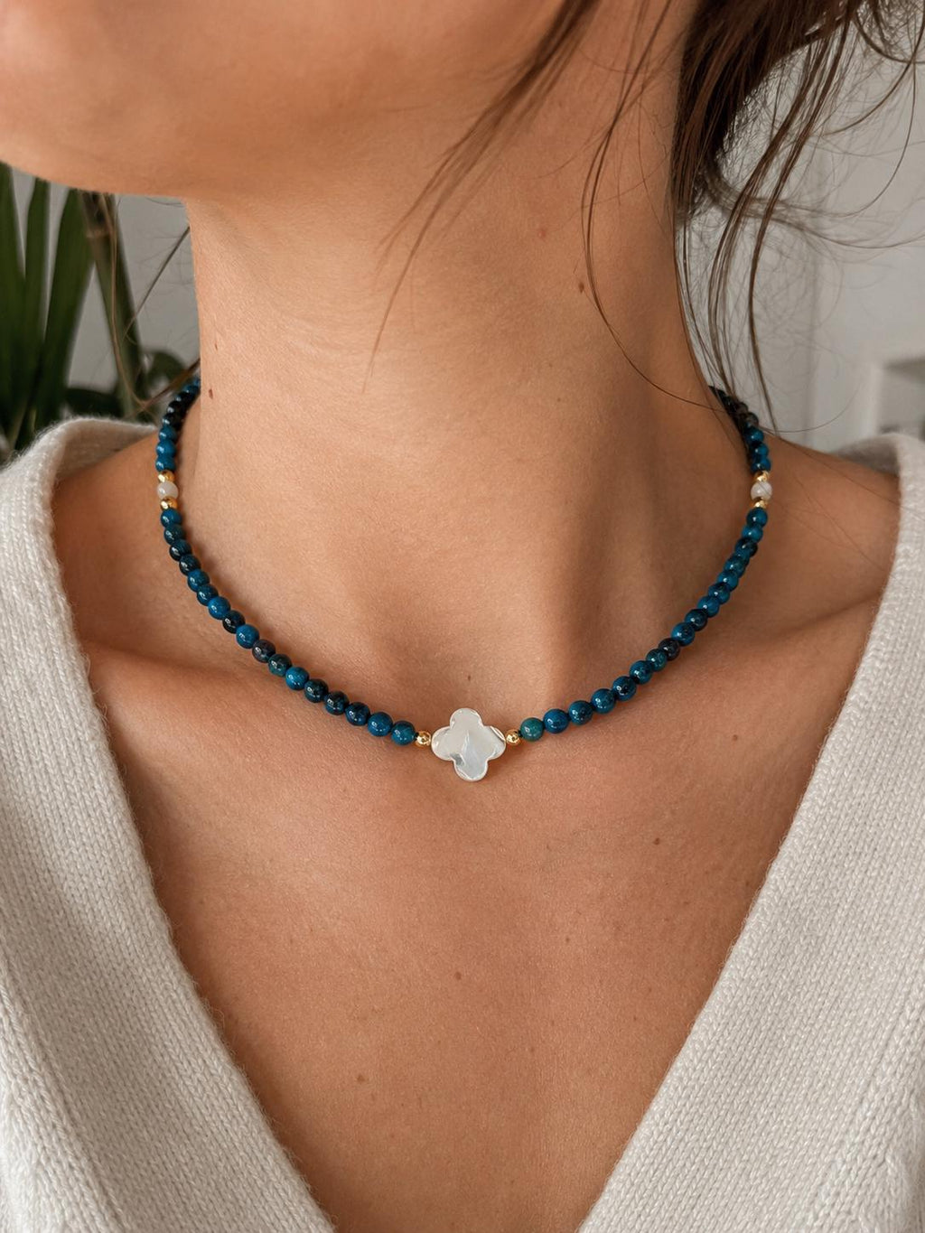 Collier œil de tigre bleu et trèfle en nacre blanche porté au cou