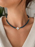 Collier œil de tigre bleu et trèfle en nacre blanche porté au cou