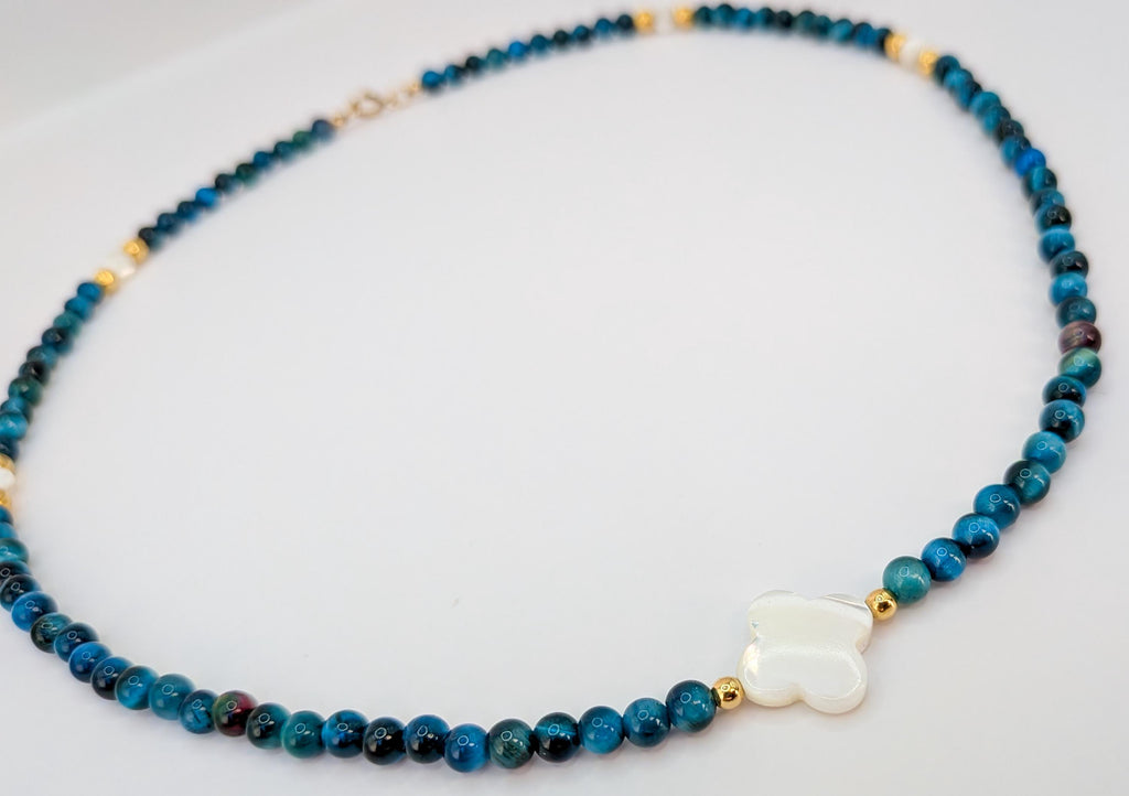 Détail du collier œil de tigre bleu, perles dorées et trèfle en nacre