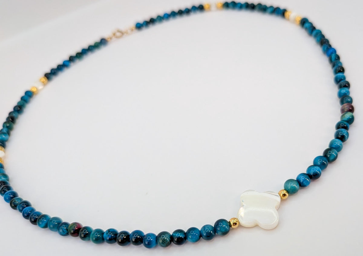Détail du collier œil de tigre bleu, perles dorées et trèfle en nacre