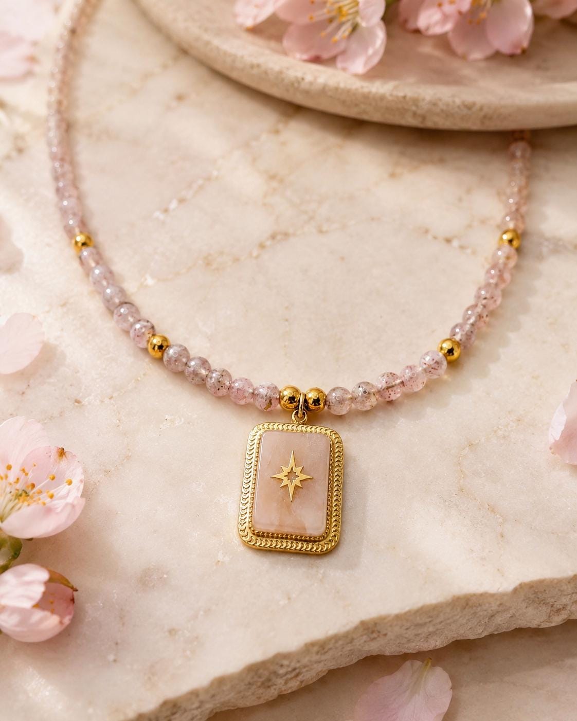 Détail du pendentif étoilé et des perles roses sur une pierre claire