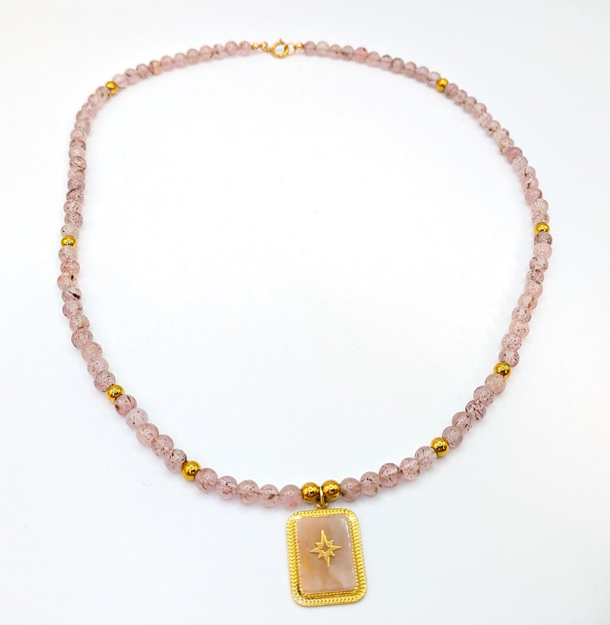 Vue complète du collier quartz fraise et détails dorés sur fond blanc